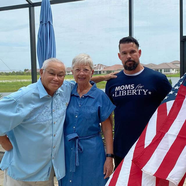 older-couple-stand-next-to-gentleman-with-usa-flag